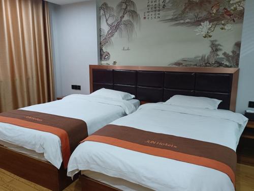 two beds sitting next to each other in a room at JUN Hotels Jiangxi Yingtan Yujiang County Railway Station Store in Yingtan