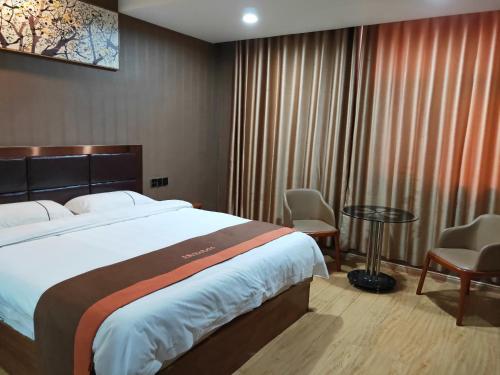 a bedroom with a bed and a table and chairs at JUN Hotels Jiangxi Yingtan Yujiang County Railway Station Store in Yingtan