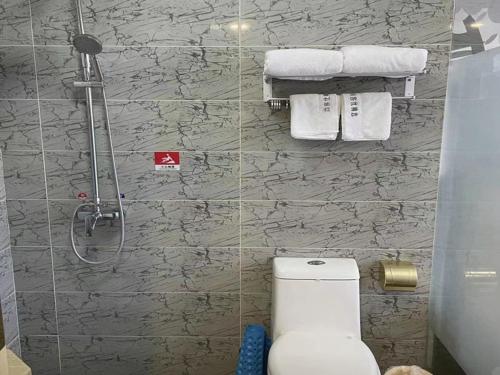 a bathroom with a shower and a toilet and towels at Thank Inn Chain Hotel hebei langfang gymnasium in Langfang