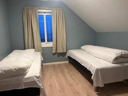 two beds in a small room with a window at House by the ocean with midnight sun view in Eggum