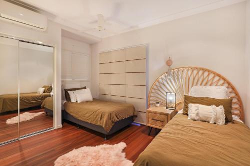 1 dormitorio con 2 camas y espejo en Luxury Holiday Home in Alex - Heated Pool - Pets Allowed, en Alexandra Headland