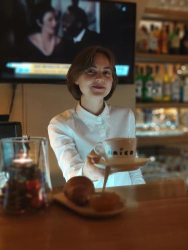 a woman sitting at a counter with a cup of coffee at Hotel Lindenhof in Bad Gastein