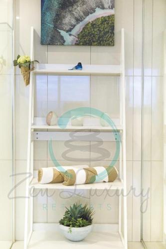 a white shelf with pillows and a plant on it at ZEN SEA BREEZE - Darwin's Premier Family Apt in Darwin