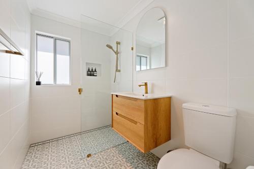 Un baño blanco con inodoro y lavabo. en Megalong Valley Lookout Cottage, en Katoomba