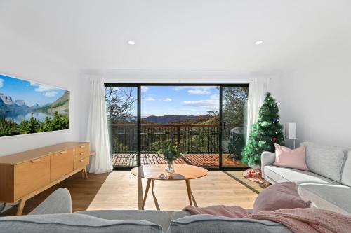 a living room with a couch and a large window at Megalong Valley Lookout Cottage in Katoomba