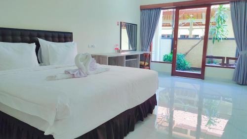 a bedroom with a white bed with a stuffed animal on it at THE LAVIANA HOTEL in Lovina
