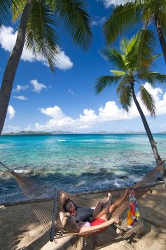 two people laying in a hammock on a beach at Gallows Point Resort in Saint John