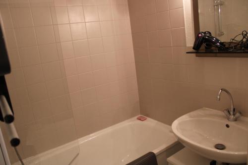 La salle de bains est pourvue d'une baignoire blanche et d'un lavabo. dans l'établissement Les Pierres Blanches Contamines Montjoie, aux Contamines-Montjoie