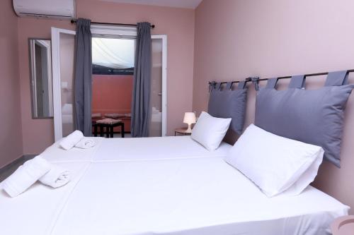 een slaapkamer met 2 witte bedden en een raam bij Casa Di Nina in Ýpsos