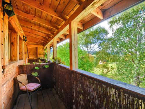 a porch of a cabin with a chair and a window at Gościniec Rabe - Agro&SPA in Ustrzyki Dolne