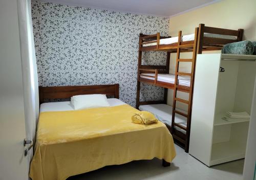1 dormitorio con 2 literas y colcha amarilla en Kit Dona Branca, en Alto Paraíso de Goiás