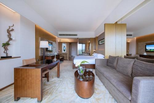 a hotel room with a couch and a bed at Mission Hills Hotel Resorts Dongguan in Dongguan