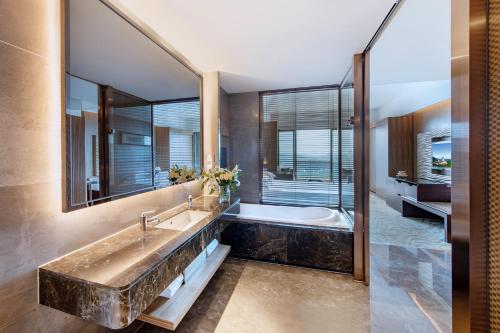 a bathroom with a large tub and a large mirror at Mission Hills Hotel Resorts Dongguan in Dongguan