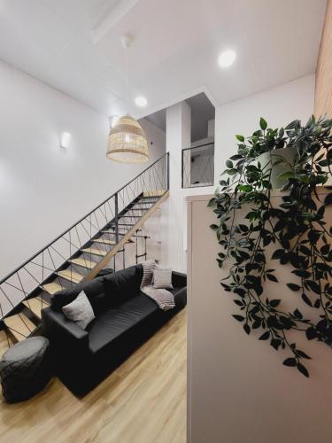 a living room with a black couch and a staircase at Carbonell 1 in Valencia