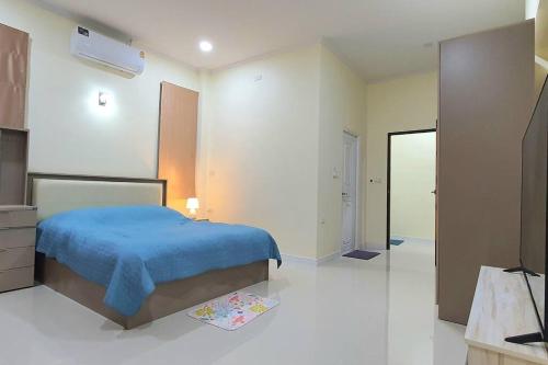 um quarto com uma cama com um cobertor azul em Happy Family em Chanthaburi