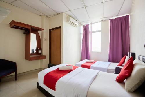 two beds in a hotel room with purple curtains at Jerteh Hotel, Terengganu in Jertih