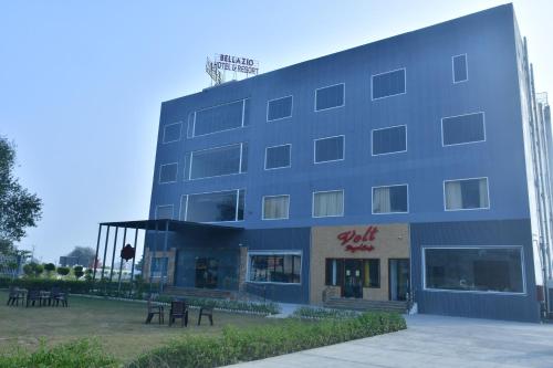 un bâtiment bleu avec des tables devant lui dans l'établissement Bellazio Suites Hotel & Resort, à Bareilly
