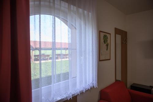 a window with a white curtain and a red couch at Penzion Sudomír in Sudoměřice