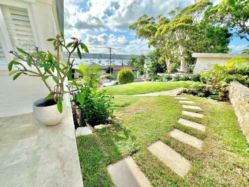 a garden with a stone walkway next to a house at The Boathouse at Whitesands Cronulla in Cronulla