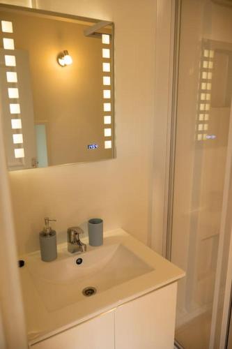 une salle de bain blanche avec un lavabo et un miroir dans l'établissement Petite Maison située entre Saint-Malo et Cancale, à Saint-Méloir-des-Ondes