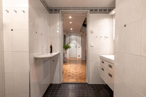 a bathroom with white tiles and a sink and a hallway at 2ndhomes Luminous & Modern 107m2 Penthouse in Kruununhaka in Helsinki