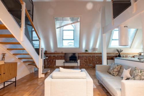 ein Wohnzimmer mit einer weißen Couch und einer Treppe in der Unterkunft 2ndhomes Luminous & Modern 107m2 Penthouse in Kruununhaka in Helsinki