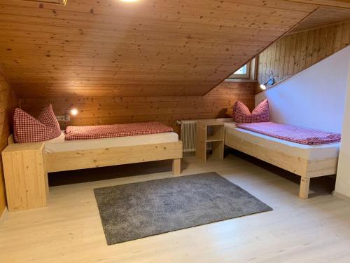 a attic room with two beds and a rug at Haus Angelika in Innerbraz