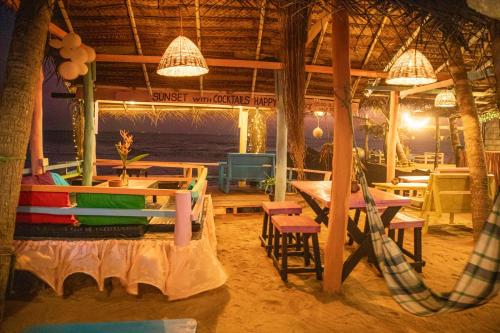 ein Restaurant am Strand mit Tischen und Stühlen in der Unterkunft Oynise Beach Cabin in Galle