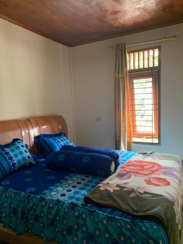 a bedroom with a bed with blue sheets and a window at Anna’S in Tuktuk Siadong