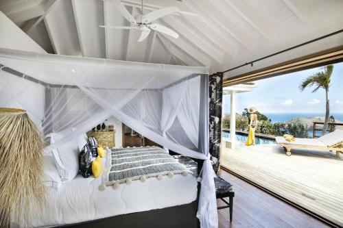 a bedroom with a canopy bed with a view of the ocean at GYP SEA Saint Barth in Gustavia