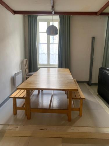 una mesa de madera en una sala de estar con sofá en Appartement WOAN centre Marciac, en Marciac