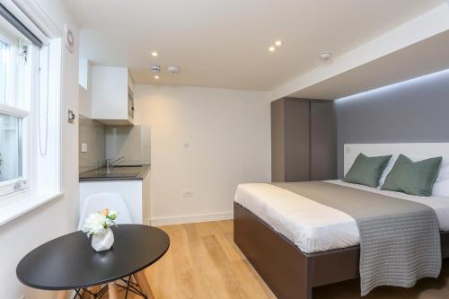 Dormitorio pequeño con cama y mesa en Inverness Terrace Serviced Apartments by Concept Apartments, en Londres