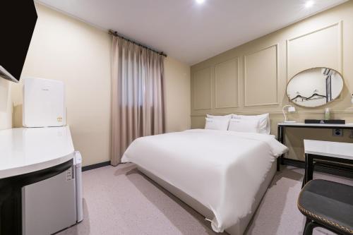 a bedroom with a large white bed and a desk at Hotel Rodem in Incheon