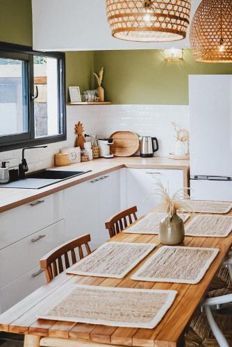 a kitchen with a wooden table with chairs and a counter at Villa Couleur Nature in Salazie