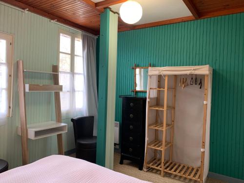 Dormitorio con paredes verdes, cama y estante en Appartement WOAN centre Marciac, en Marciac