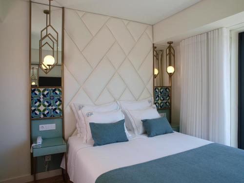 Un dormitorio con una cama blanca con almohadas azules y blancas en New Style Lisbon Hotel en Lisboa