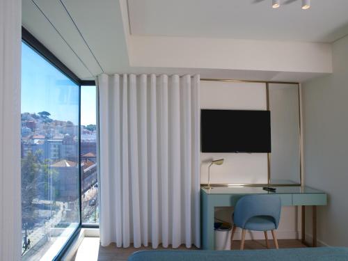 a bedroom with a desk and a large window at New Style Lisbon Hotel in Lisbon