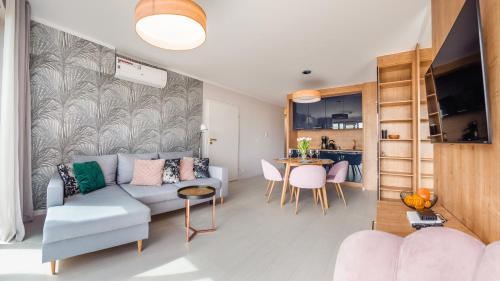 ein Wohnzimmer mit einem Sofa und einem Tisch in der Unterkunft Apartamenty Sun & Snow Kołobrzeg Resorts z basenem in Kołobrzeg
