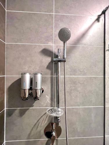 a shower with two cups on a tile wall at 2-8pax Ipoh Nomado Onsen suites by Sunway Onsen Lost world of Tambun in Ipoh