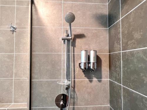 a shower with a microphone on a tiled wall at 2-8pax Ipoh Nomado Onsen suites by Sunway Onsen Lost world of Tambun in Ipoh