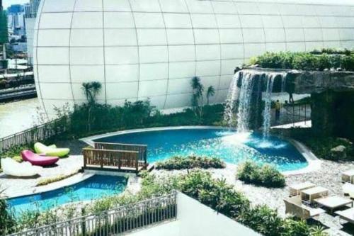 - une piscine avec une cascade en face d'un bâtiment dans l'établissement A2J 1BR Luxury River View Suite Near Rockwell Mall, à Manille