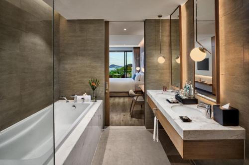 a bathroom with two sinks and a tub and a bedroom at Premier Residences Phu Quoc Emerald Bay Managed by Accor in Phu Quoc