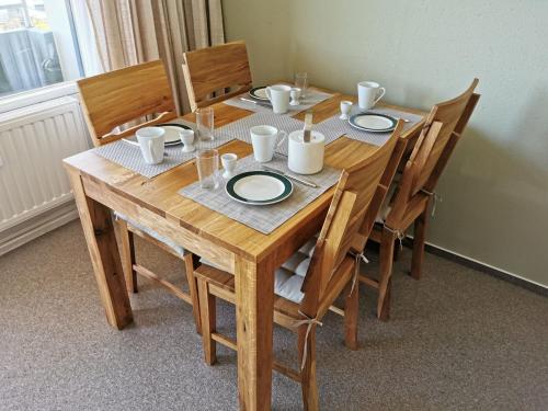 einem Holztisch mit Tellern und Tassen darauf in der Unterkunft Vier Jahreszeiten I 50 in Großenbrode
