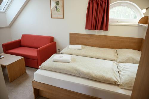 a bedroom with a bed and a red chair at Penzion Sudomír in Sudoměřice