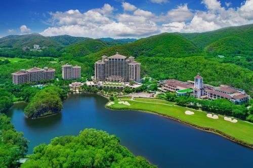 an aerial view of a resort with a lake and mountains at Mission Hills Hotel Resorts Dongguan in Dongguan
