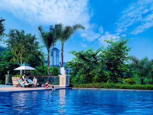 people sitting on a bench next to a swimming pool at Mission Hills Hotel Resorts Dongguan in Dongguan