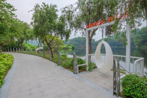 a sign at the end of a path next to a lake at Mission Hills Hotel Resorts Dongguan in Dongguan