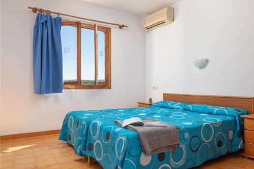 sypialnia z łóżkiem z niebieską pościelą i oknem w obiekcie Holiday Park Santa Ponsa w miejscowości Santa Ponsa