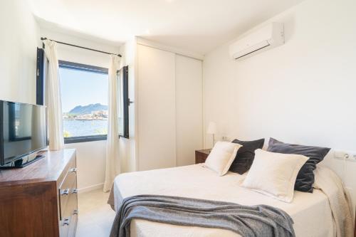 ein Schlafzimmer mit einem Bett, einem Fernseher und einem Fenster in der Unterkunft Seashore House " Es tamarells" in Alcúdia