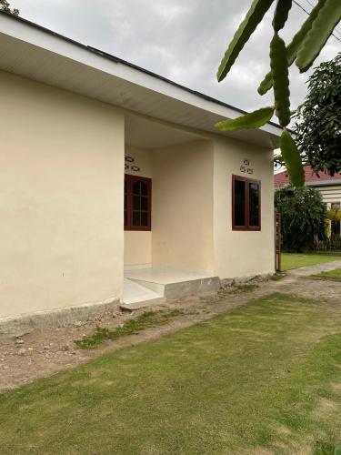a white house with a grass yard at Paima Homestay in Balige